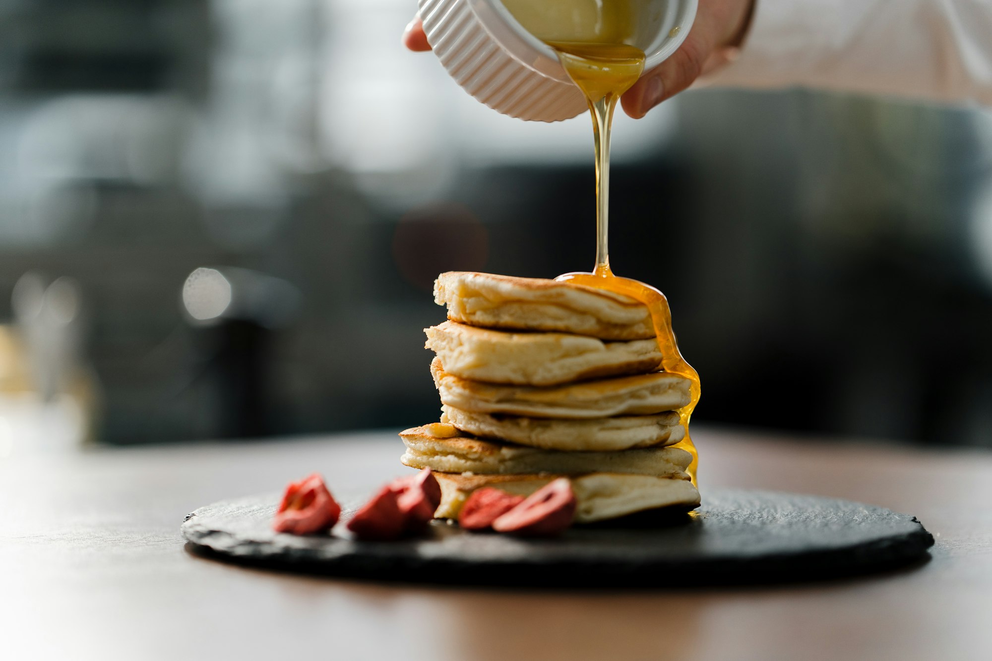 Pancakes with strawberries for breakfast the cook pours honey over the pancakes